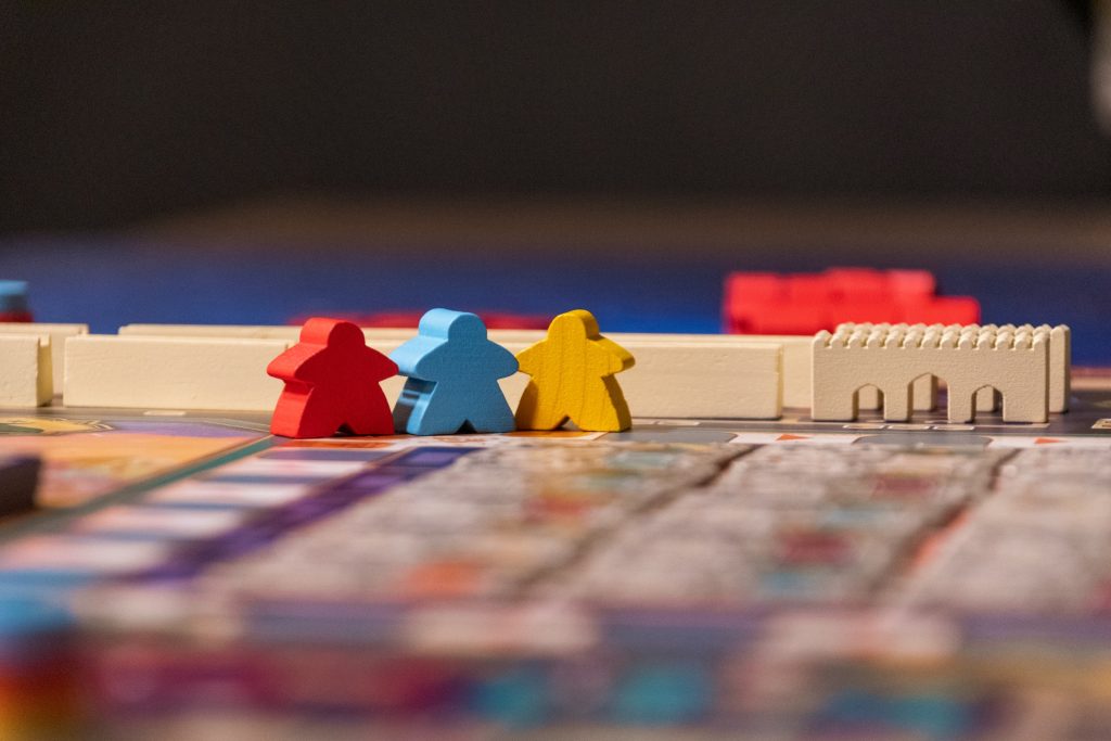 Red, blue, and yellow meeples standing on a board game board